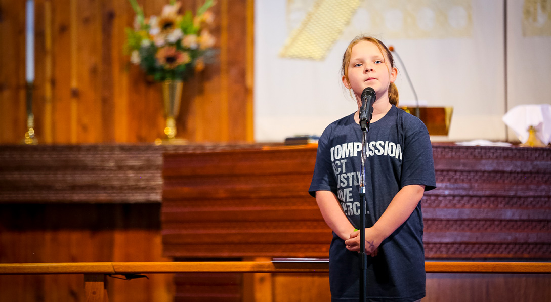 a young girl stands in front of a microphone